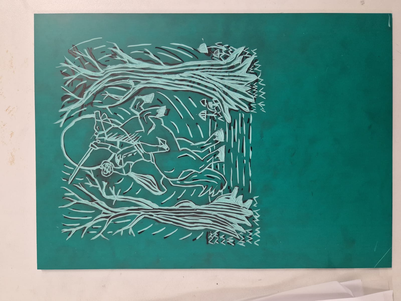 Close-up of hand-carved lino block showing the subtractive carving process — tools, ink, and cut block detail